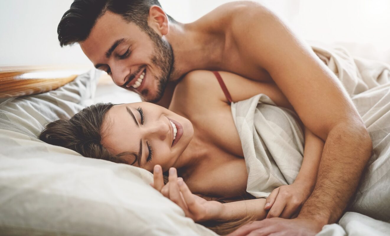 Happy couple having fun on bed under blanket - Young romantic lovers intimate moments