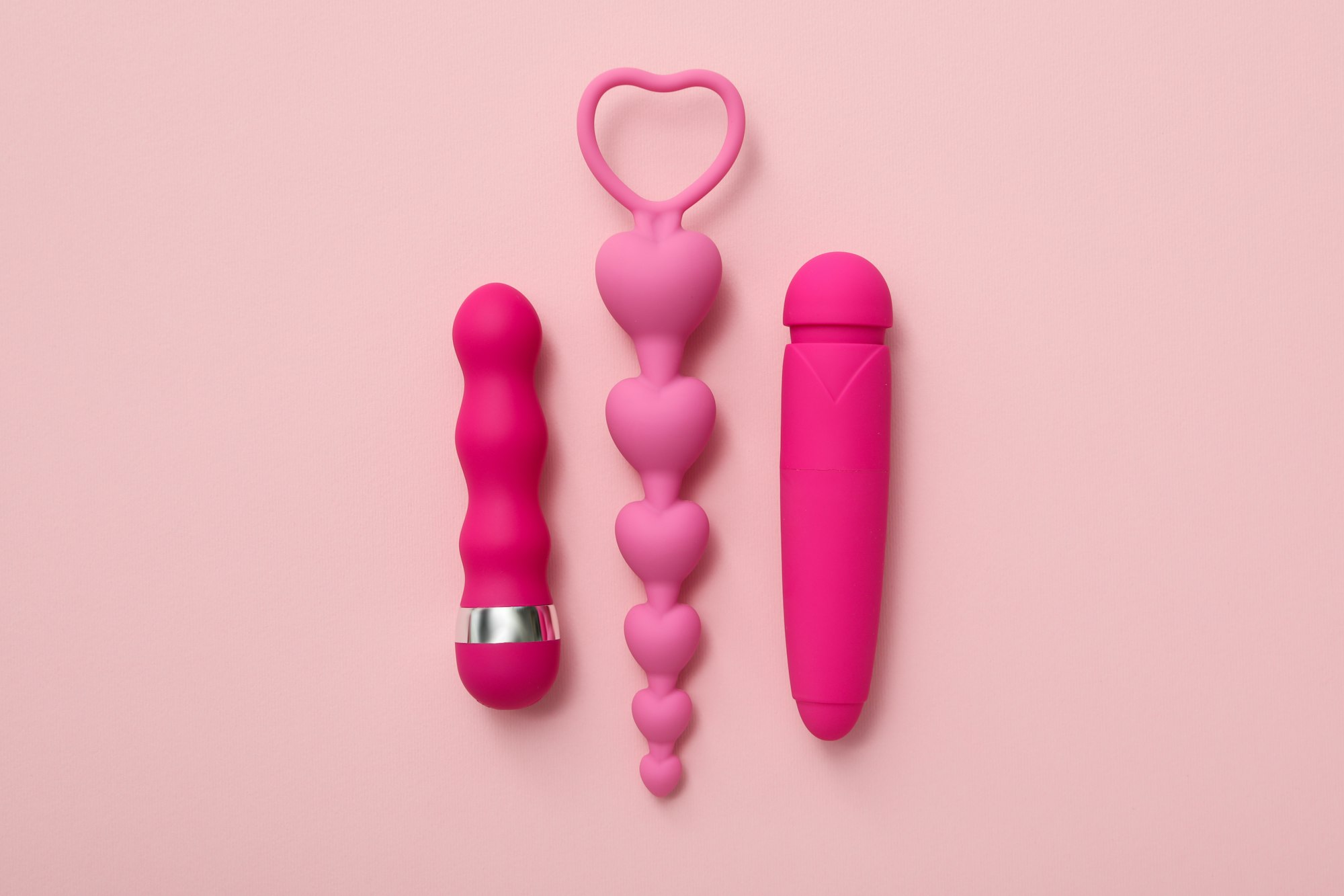 Collection of sex toys, on a pink background.